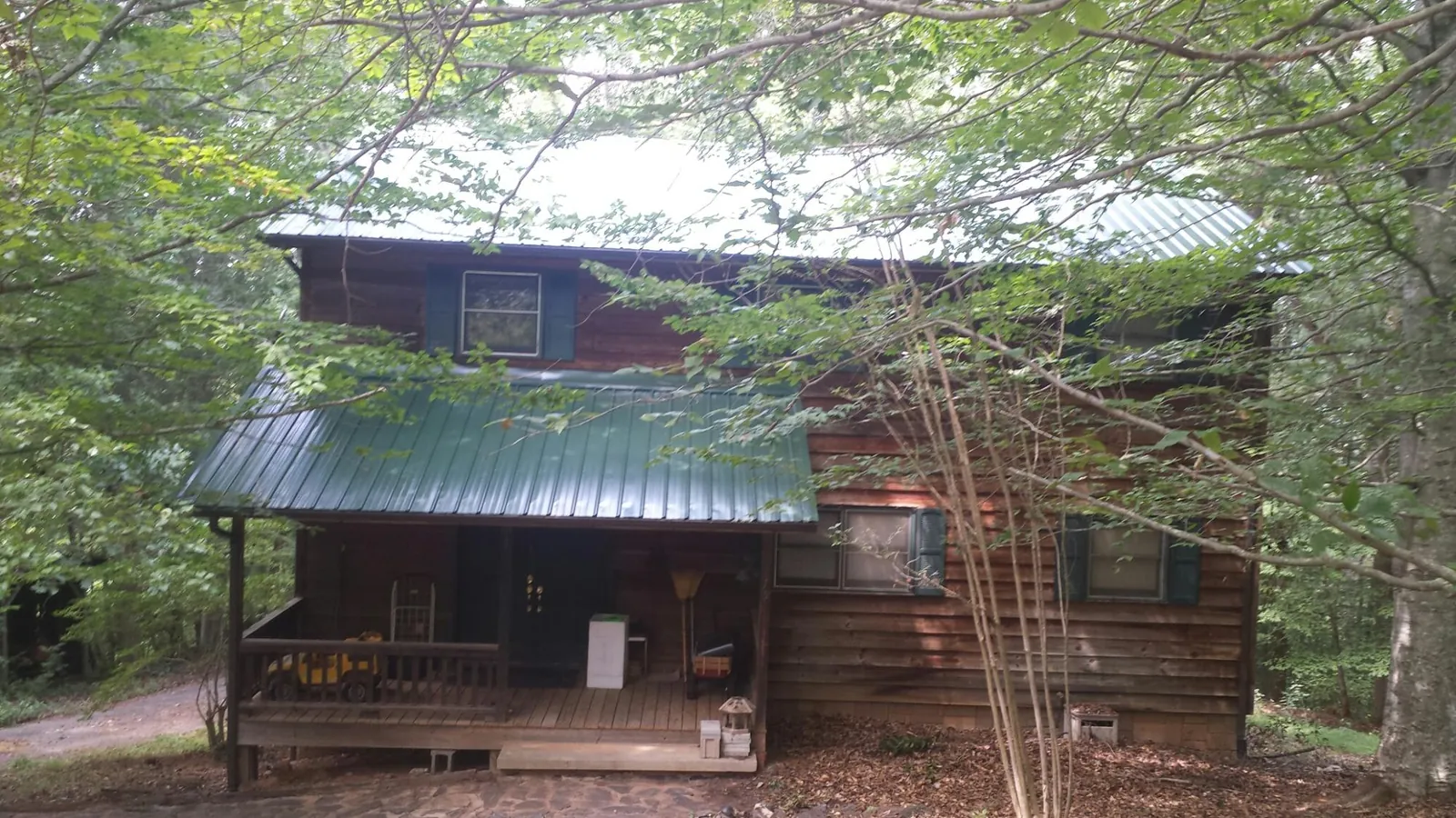 Green metal roof and covered porch on a log cabin in Acme