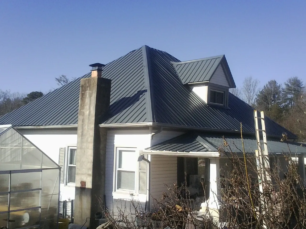 Dark blue standing seam metal roof on a white farmhouse with dormer — Slate & Tile Roof Repair by Roofing Brothers in Acme