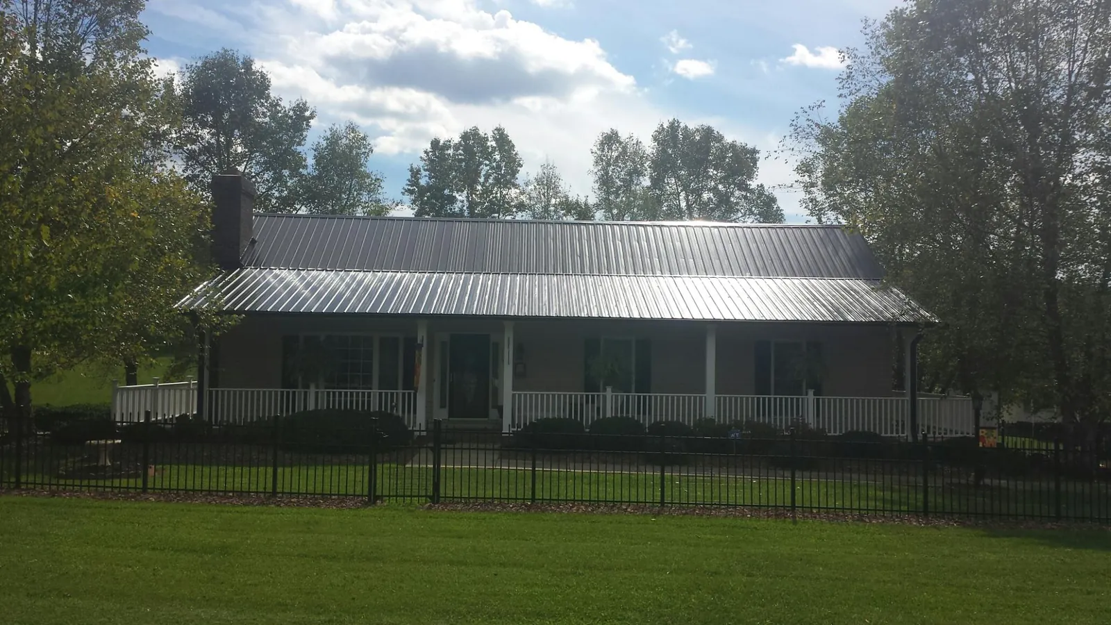 Gray metal roof on a brick ranch with a full width front porch — Gutter Guard Installation work by our crew in Acme