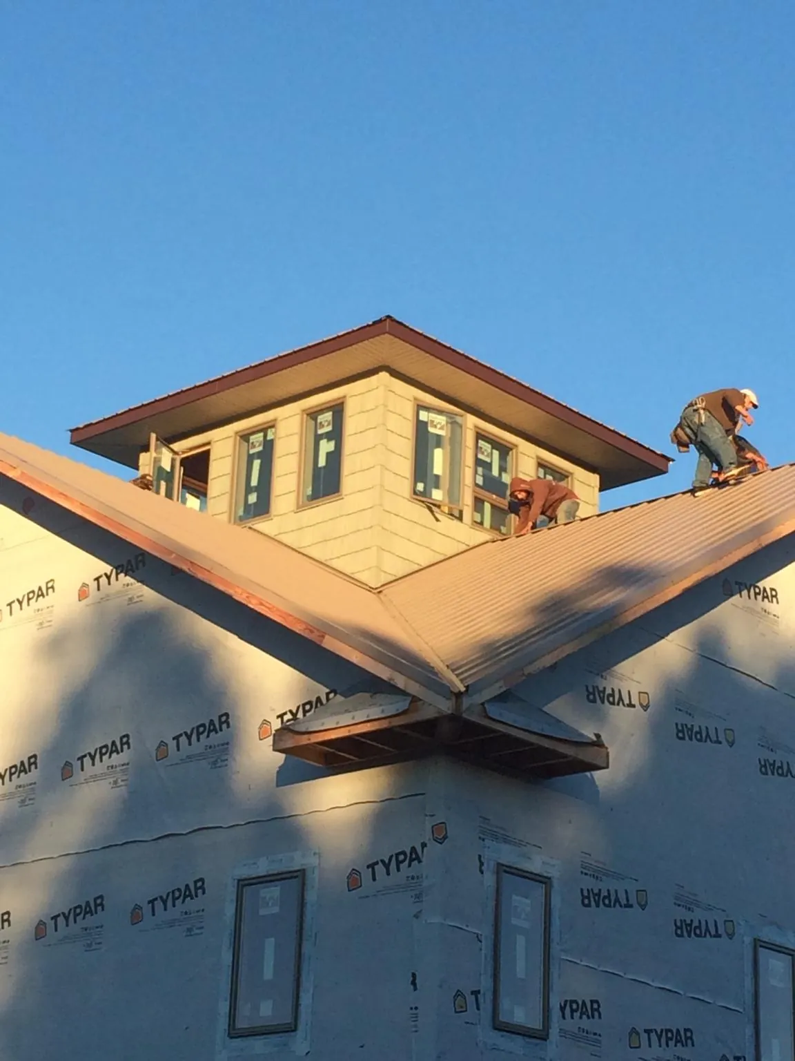 Roofers working around a rooftop cupola on a new metal roof at sunset — Roof Waterproofing in Acme by Roofing Brothers